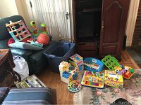 Photo showing multiple toys including shape sorter, basketball toy, stacking toys, and large blue storage bin