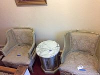 Pair of two vintage upholstered chairs beside a marble topped side table, chairs show wear and discoloration.