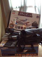 Photo showing stacked electronics including Striker Spy Drone box, Sony Handycam, Samsung DVD/VHS player box
