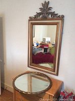 View of full rectangular mirror hanging on wall above round mirror showing carved wood frame and room reflection