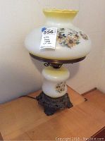 Full view of glass dome lamp showing floral motif on dome and base, scalloped top edge, small chip marked with blue tape