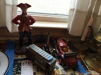 Photo showing multiple vintage travel decor items on a window sill including the British soldier, wooden car, and cable car replicas