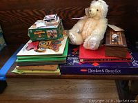 Photo showing the Hermann bear, card games, and wooden puzzles stacked on a blue table.