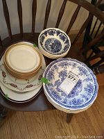 Photo of stacked plates and bowls showing blue and white Limoges J. Pouyat bread plates, blue patterned large Luneville The Cottage bowls, and several Wedgwood bowls.