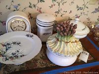 Overview photo showing the mantle clock, Gevalia canister, asparagus casserole, cake plate, and hot dog server