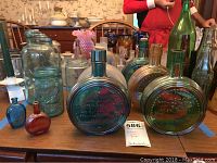 Photo showing Wheaton Glass Atlas EZ Seal jars, Mason and Ball jars, and several vintage collectible glass bottles in various sizes and colors on a table.