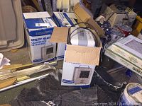 Three boxed Workforce utility heaters shown in a cluttered storage space, one box open with a heater visible inside.