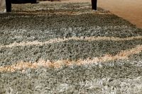 Close-up showing the wavy sage and cream striped pattern and shag texture.