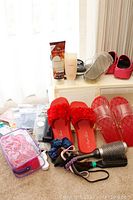 Photo showing 5 pairs of women's beach shoes in different styles and colors, unopened hair products, medium size unopened nylons, sleep mask, and additional hair accessories including scrunchies and a hairbrush.
