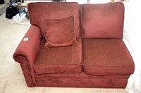 Front view of right arm couch showing textured reddish-brown upholstery and matching throw pillow on left corner.
