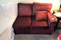 Full left arm front view of the dark reddish custom fabric couch with two seat cushions, two back cushions, and a small throw pillow.