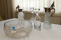Four crystal decanters, one punch bowl with ladle, and one vase arranged on table