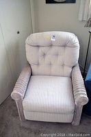 Front view of recliner chair showing padded backrest and seat cushion with striped upholstery and wicker arms.