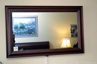 Front view of TV powered off, showing mirror-like reflective frame and glass surface.