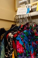 Photo of multiple women's dress blouses hanging on a rack, showing various colorful patterns and styles.