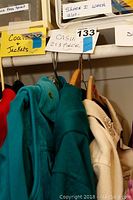 Close-up photo showing different clothing sections labeled as 'Coats Jackets' and 'CASUAL 2:3 PIECE' with clothing items hung on hangers.