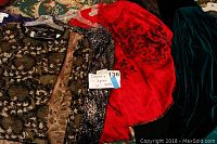 Photo showing multiple women's dressy 2 and 3 piece sets with various fabric textures and colors including floral patterns and velvet in dark tones with a bright red dress.