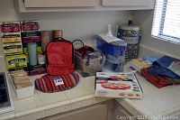 Full view of kitchen counter showing teas, fabric bags, cookbook box, blue filter pitcher, and woven baskets with kitchen items.