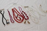 Overall photo of the jewelry collection showing lined up necklaces, earrings, and bracelets in various colors including black, red, rose, and clear crystal beads.