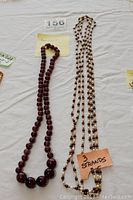 Photo showing the round amethyst bead necklace on the left and the three-strand freshwater pearl and amethyst bead necklace on the right.