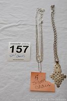 Photo showing five thin sterling silver chains and one thicker chain with a sterling silver pendant attached.