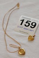 Chain and smaller heart pendant alongside lot card