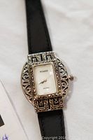 Front angle of ladies wristwatch showing marcasite-studded bezel, rectangular white dial with Visage branding, and black leather strap.