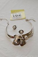 Photo showing sterling silver choker necklace with floral design and mabe pearl, alongside matching earrings each with mabe pearl