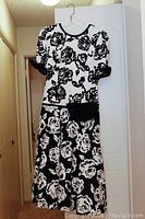 Ankle-length black and white floral dress with short sleeves and waist details.