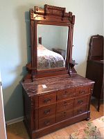 Front view of antique wooden dresser with marble top and attached swing mirror