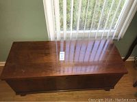 Top view of antique cedar chest showing rectangular polished wood surface with slight scratches and wood grain.