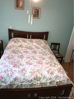Full bed made up with floral bedding showing headboard and side view