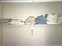 Full view of collection of folded bed linens on shelf including various colors and patterns