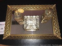 Vintage vanity set displayed on black surface showing the mirrored tray, two perfume bottles with gold filigree, and a glass trinket dish.