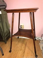 Side and partial front view of the antique claw side table showing wood grain and positioning of legs and casters.