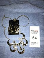 Full view of silver necklace with crescent moon pendants, matching earrings, ring, and bracelets on blue fabric background