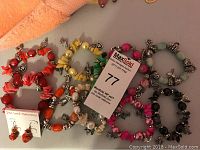 Photo showing full collection of bead charm bracelets in various colors and one pair of red beaded earrings on card.