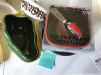 Top-down view of salsa and guacamole set including green chili pepper-shaped bowl, white 'Mucho Guac' bowl, and boxed hand-painted ceramic dip set with chili pepper design knife.