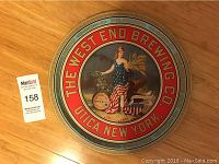 Front side of the round metal tray showing The West End Brewing Co. logo and patriotic woman graphic on colorful background.