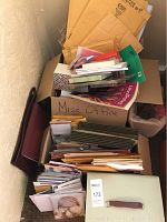 Top down view of cardboard boxes packed with office supplies including notebooks, envelopes, folders, binders.