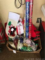 Photo of Christmas stockings, assorted bows, and rolls of wrapping paper in a box.