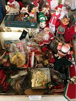 Overview of vintage Christmas ornaments and various Santa and elf figurines with other decor piled in a box.