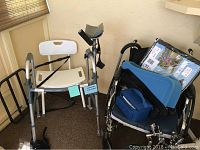 Photo showing white plastic shower seat, silver walker with arm support, black cane, black bed rail, wheelchair with blue cushion and blue carrying bag