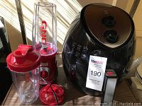 Photo showing Farberware air fryer beside GNC smoothie maker with blending cups and lids on a wooden surface.