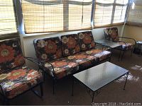 Full view of the 5-piece vintage patio furniture set with metal frames and floral cushions positioned near window blinds.