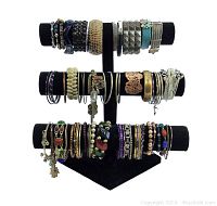Front view of over 60 bracelets of various styles, materials and colors on a three-tier black velvet display stand.