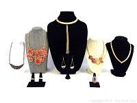 Full view of the lot including five necklaces, a pair of earrings, and three rings on display mannequins and stands