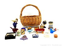 Photo showing 20 assorted knick-knacks in front of a wicker basket including cobalt blue glass vase, miniature globe, hourglass, red wooden toy wagon, ceramic boxes, and others.