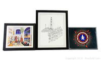 Three art prints side by side including interior scene, cityscape line drawing, and superhero shield design, all framed in black.