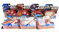 Photo showing 7 vintage Star Wars ship figurines with original packaging laid out in two rows, clear plastic blister packs on Star Wars Hot Wheels cards, includes ships like Millennium Falcon and Slave 1.